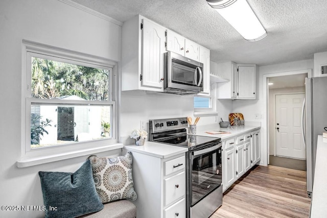 kitchen featuring stainless steel appliances, plenty of natural light, light countertops, and white cabinetry