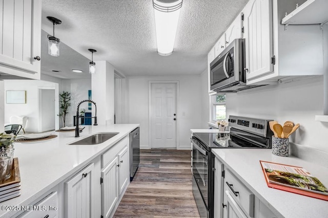 kitchen featuring light countertops, hanging light fixtures, appliances with stainless steel finishes, white cabinetry, and a sink