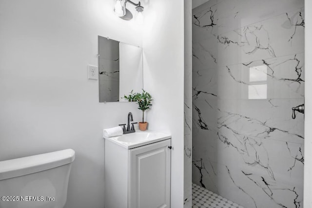 bathroom featuring toilet, a marble finish shower, and vanity