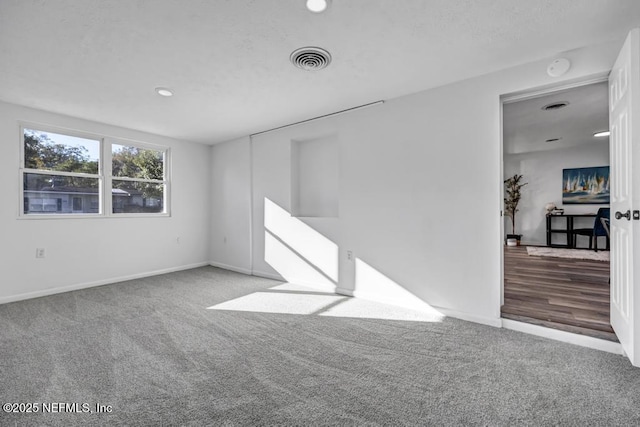 spare room with baseboards, visible vents, and carpet flooring