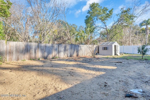 view of yard with a fenced backyard, a storage unit, and an outdoor structure