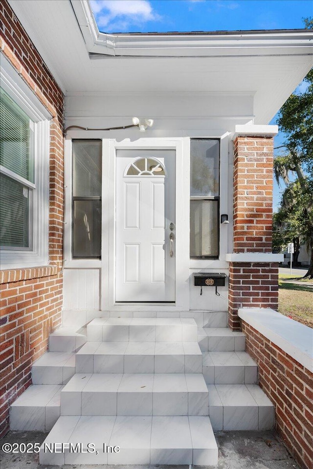 doorway to property with brick siding