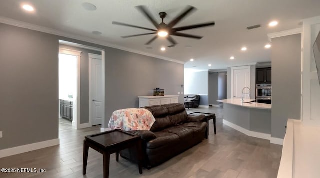 living area with crown molding, recessed lighting, visible vents, light wood-style floors, and baseboards