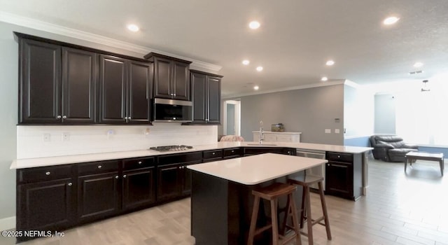 kitchen with a center island, a peninsula, light countertops, stainless steel appliances, and a sink