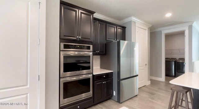 kitchen featuring crown molding, washing machine and clothes dryer, stainless steel appliances, light countertops, and light wood-type flooring