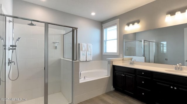 bathroom featuring a garden tub, double vanity, a stall shower, and a sink