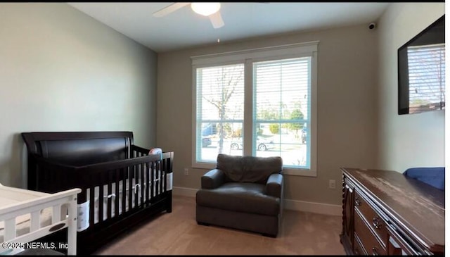 bedroom featuring a crib, baseboards, and a ceiling fan