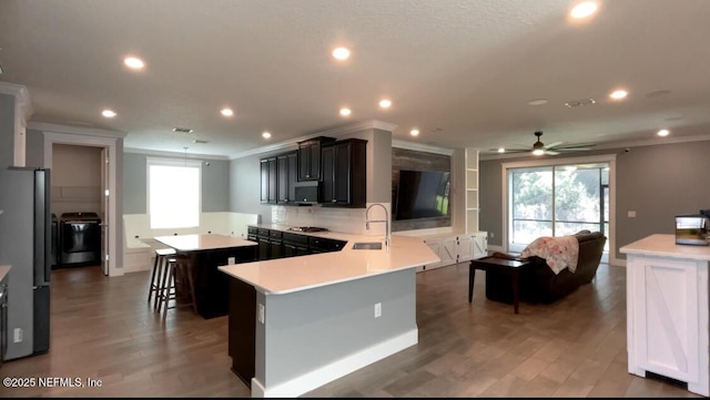 kitchen featuring a center island, light countertops, appliances with stainless steel finishes, ornamental molding, and a sink