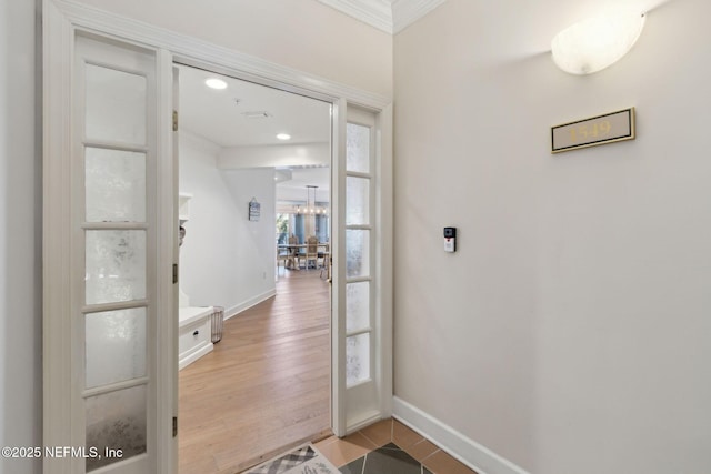 doorway featuring ornamental molding, baseboards, and wood finished floors