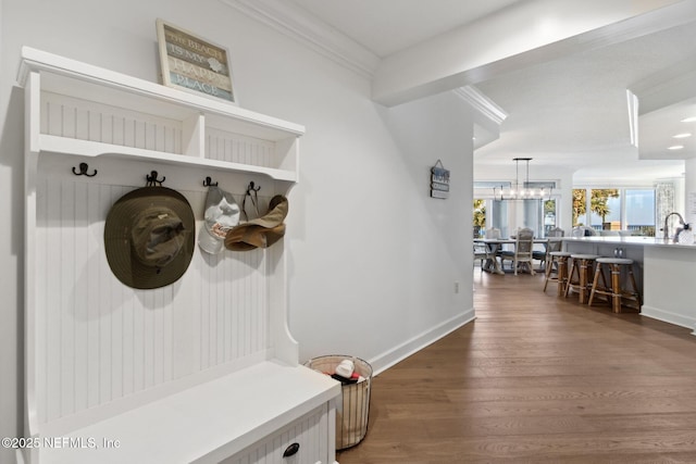 mudroom featuring ornamental molding, baseboards, dark wood finished floors, and a sink