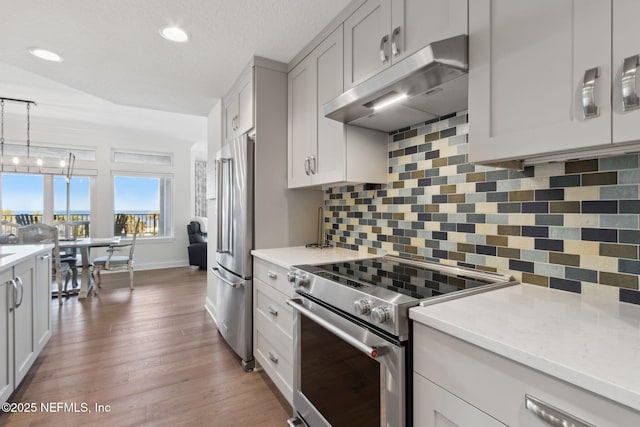 kitchen with white cabinets, stainless steel appliances, decorative light fixtures, and under cabinet range hood