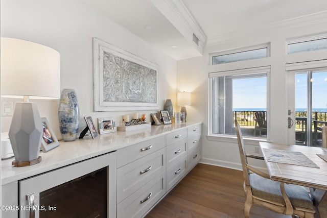 interior space featuring dark wood-style floors, ornamental molding, visible vents, and baseboards