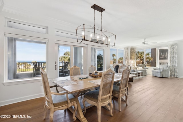 dining room with baseboards, ornamental molding, wood finished floors, and ceiling fan with notable chandelier