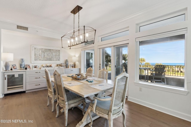 dining area with beverage cooler, visible vents, baseboards, dark wood finished floors, and crown molding