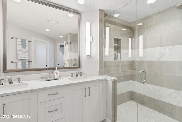 bathroom featuring double vanity, a stall shower, a sink, and recessed lighting