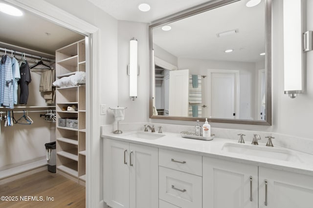 full bath with wood finished floors, a spacious closet, double vanity, and a sink