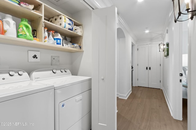 laundry area featuring arched walkways, light wood-style flooring, washer and dryer, laundry area, and baseboards