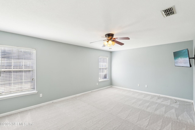 spare room with carpet floors, baseboards, visible vents, and ceiling fan