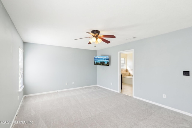 spare room with light carpet, ceiling fan, visible vents, and baseboards