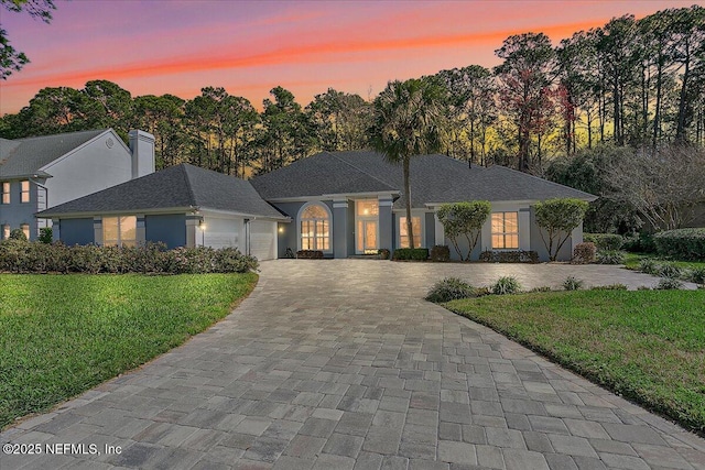 view of front facade featuring an attached garage, decorative driveway, and a front yard