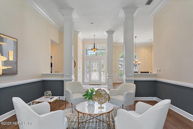 sitting room with ornamental molding, dark wood-style flooring, visible vents, and ornate columns