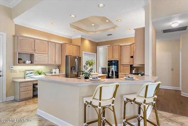 kitchen featuring stainless steel fridge, light brown cabinets, visible vents, and light countertops