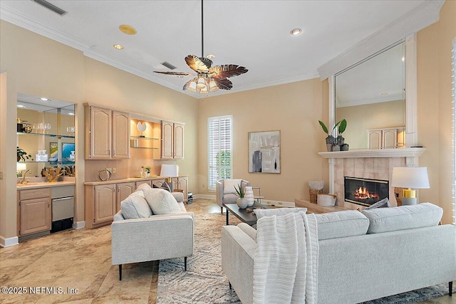 living area featuring baseboards, visible vents, a tile fireplace, ceiling fan, and crown molding