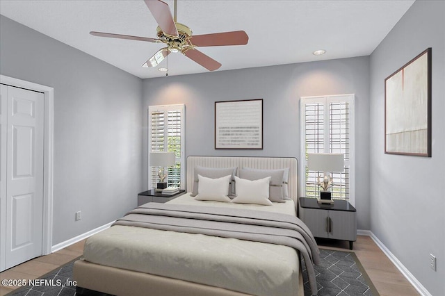 bedroom with ceiling fan, wood finished floors, and baseboards