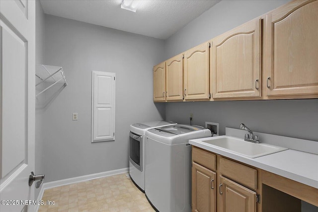 laundry room featuring a sink, baseboards, cabinet space, light floors, and washing machine and clothes dryer