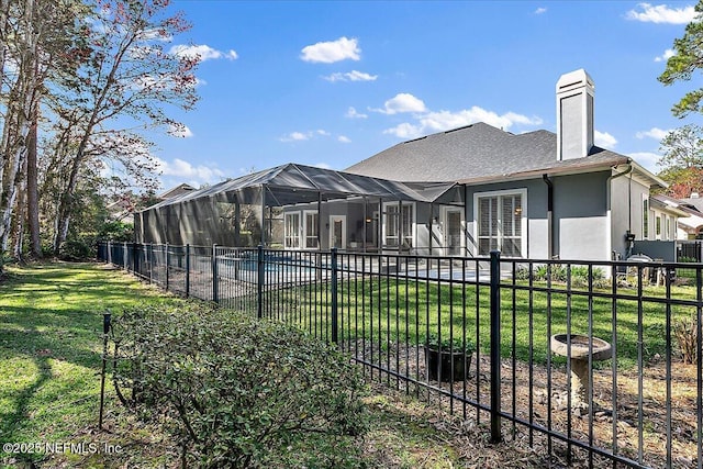 rear view of property with glass enclosure, a yard, a fenced backyard, and a fenced in pool