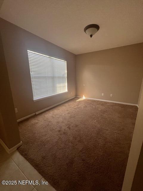 spare room featuring light carpet and baseboards