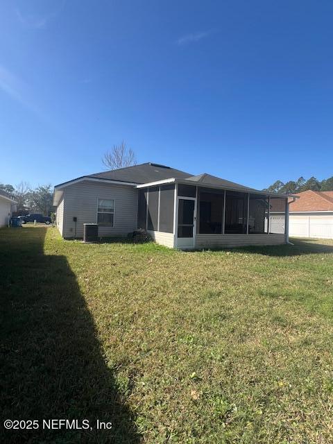 rear view of property featuring a sunroom and a lawn