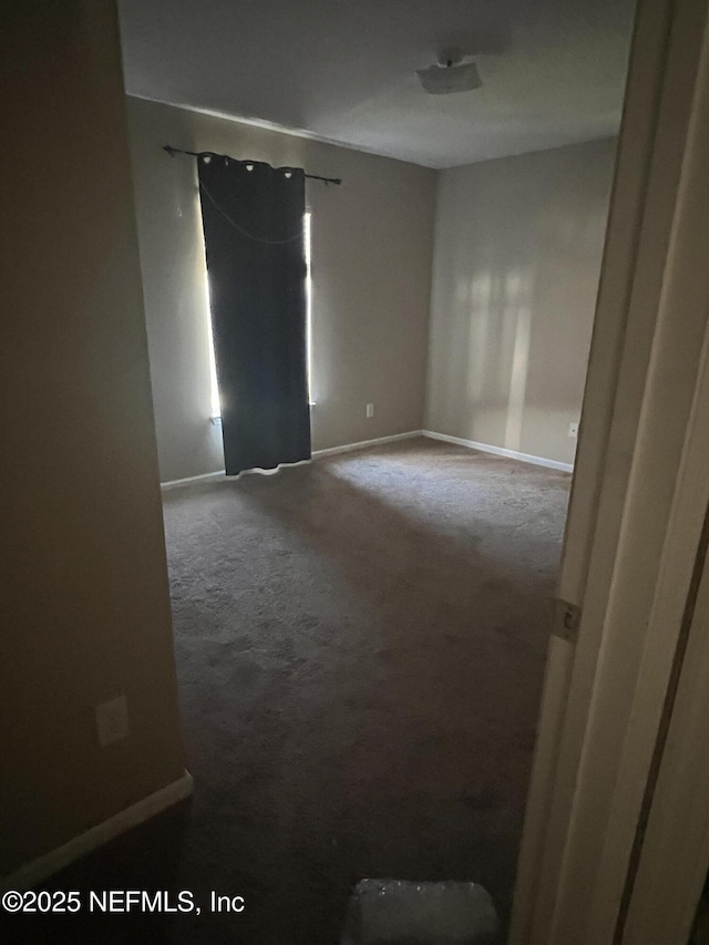 carpeted spare room featuring baseboards