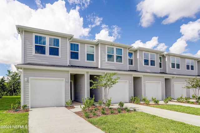 townhome / multi-family property featuring a front yard, driveway, and an attached garage