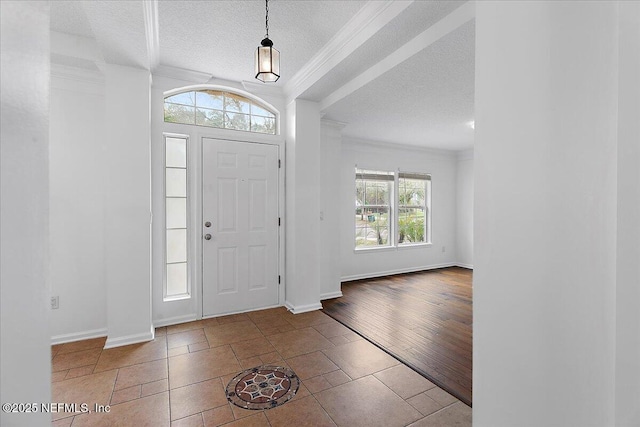 entryway with ornamental molding, a textured ceiling, and baseboards