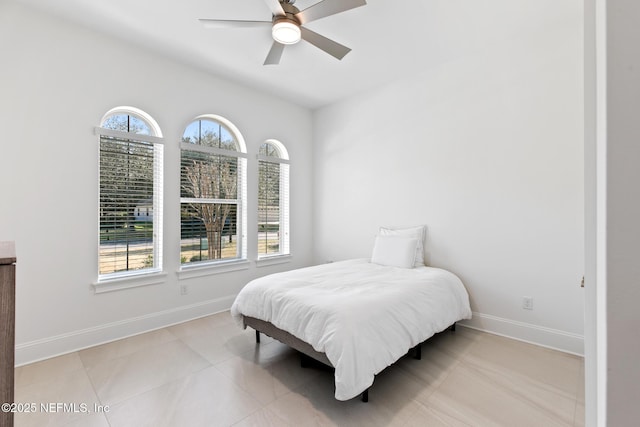 bedroom featuring a ceiling fan, baseboards, and light tile patterned floors