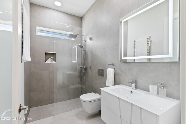 bathroom featuring toilet, vanity, tile walls, radiator, and walk in shower