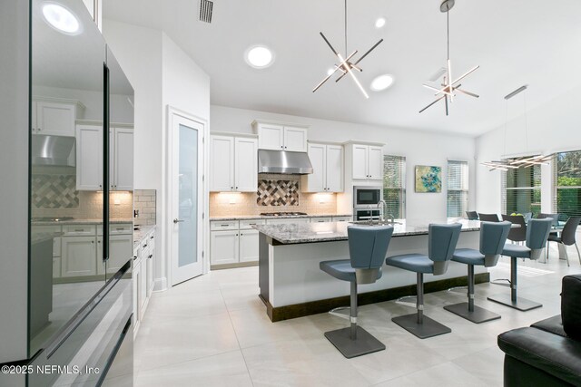 kitchen with visible vents, an inviting chandelier, stainless steel appliances, extractor fan, and under cabinet range hood