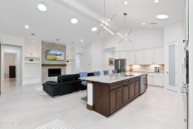 kitchen featuring a fireplace, appliances with stainless steel finishes, white cabinets, a sink, and dark brown cabinets