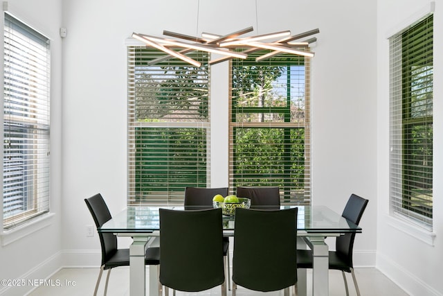 dining space with a chandelier, baseboards, and tile patterned floors