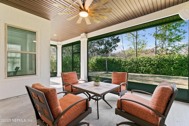 sunroom featuring a ceiling fan, a wealth of natural light, and wooden ceiling