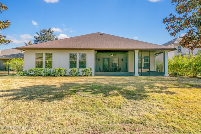 back of house with a yard, stucco siding, a shingled roof, a sunroom, and fence