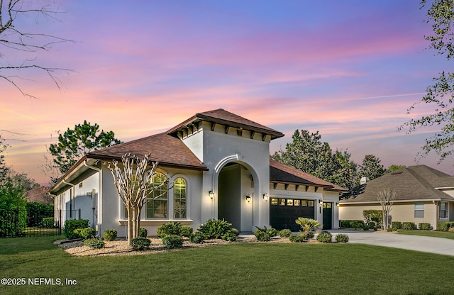 mediterranean / spanish-style house featuring driveway, a front lawn, and stucco siding