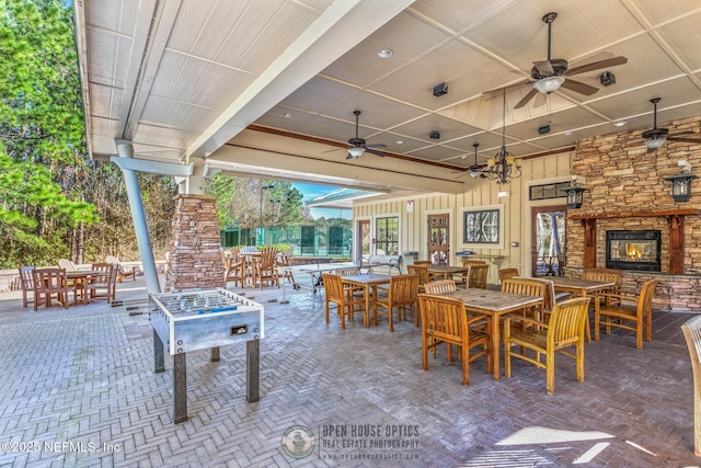 view of patio featuring ceiling fan, outdoor dining area, and an outdoor stone fireplace