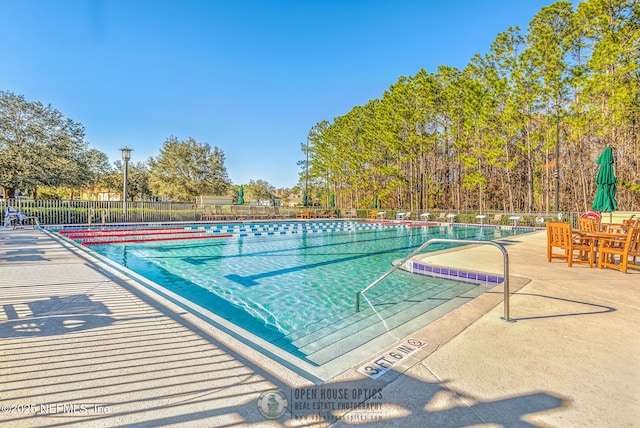 community pool with a patio area and fence