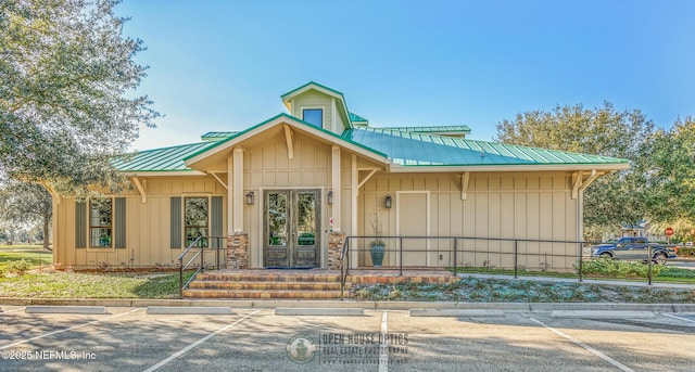 view of front of home with uncovered parking, metal roof, board and batten siding, and french doors