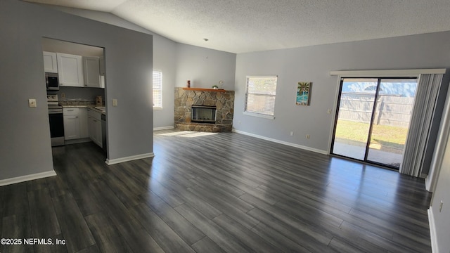 unfurnished living room with dark wood-style floors, a healthy amount of sunlight, vaulted ceiling, and a fireplace