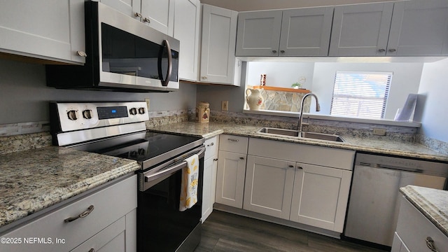 kitchen featuring stainless steel appliances, dark wood finished floors, a sink, and white cabinetry