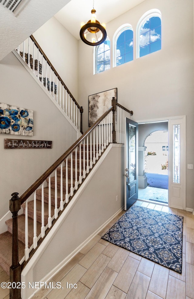 entryway with a high ceiling, baseboards, arched walkways, and wood finished floors