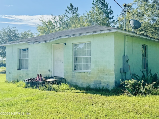 exterior space with concrete block siding and a front yard